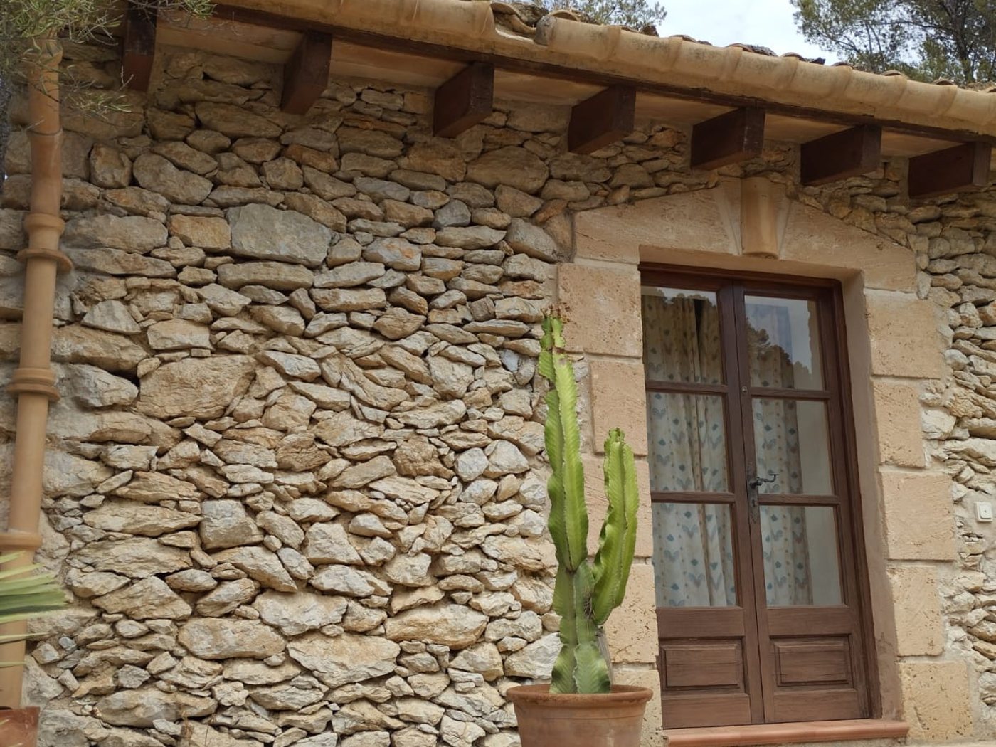 Muro de piedra en seco y marès, con puerta de madera y cubierta de teja árabe, en una finca de Andratx