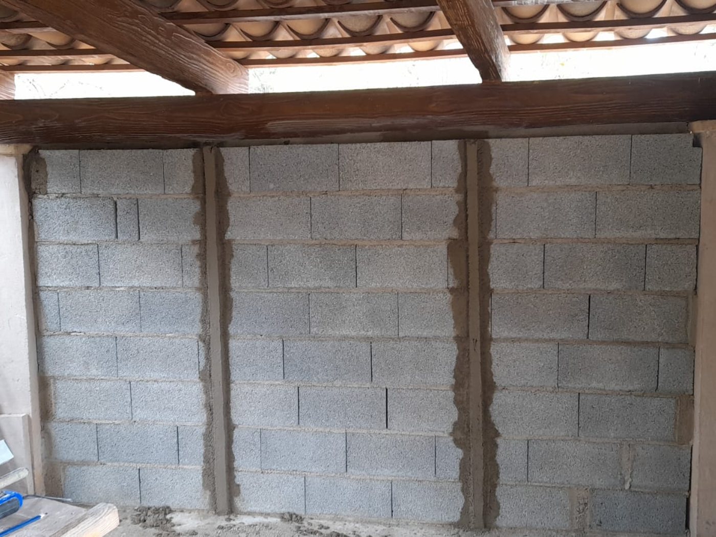 Cerramiento de bloque de hormigón con estructura de cubierta en madera y teja árabe, obra en curso